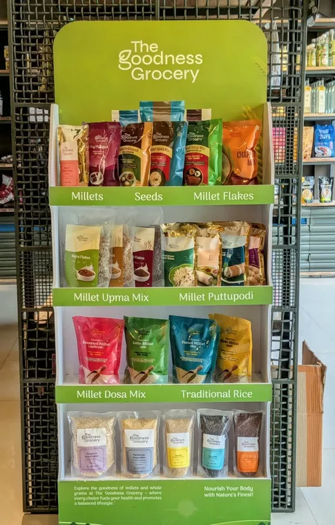 The Goodness Grocery display stand in the shop, with millets, seeds, flakes, puttupodi and dosa mixes on its shelves